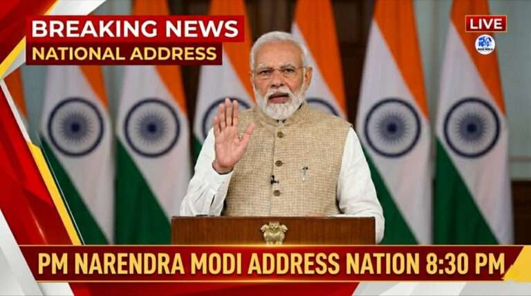 Prime Minister Narendra Modi addressing the nation at 8:30 PM with Indian flags in the background during a live national broadcast